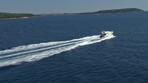 A speedboat speeds across Adriatic sea near islands. Aerial helicopter shot.