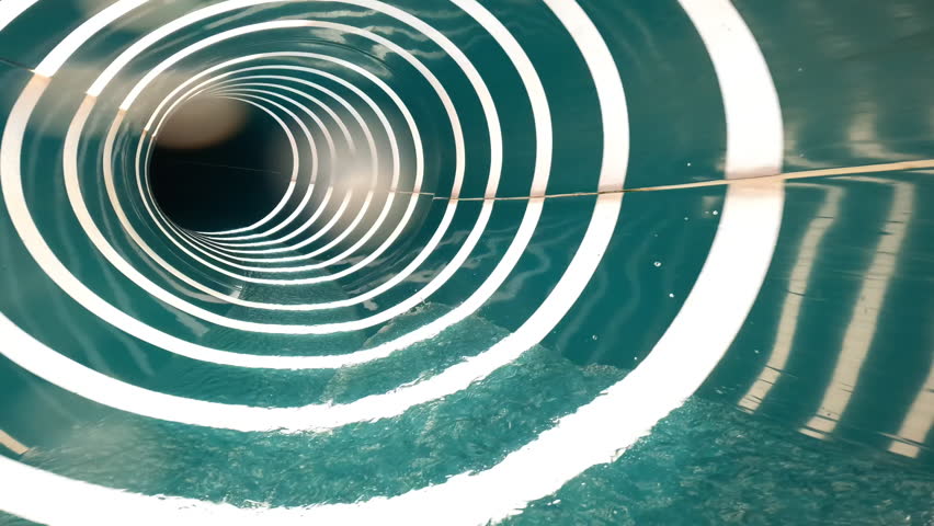 FPV perspective of water flowing swiftly through a blue water slide illuminated by bright sunlight