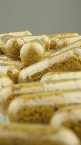 Transparent capsules with turmeric and nutrients that slowly rotate on a white background. An Ideal Way to Achieve Health and Cure. 