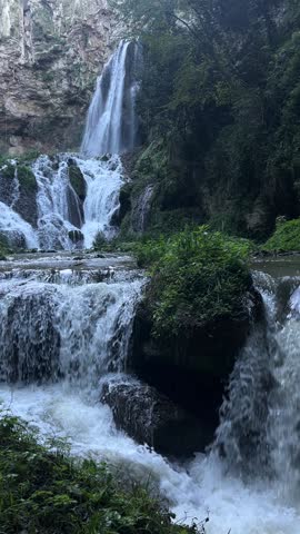 Cascading waterfall in Tivoli, Italy, surrounded by lush greenery. Natural, peaceful water flowing between stones and leafs.