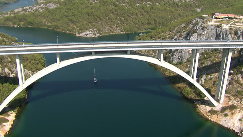 Zooming-in to a car driving across the Krka bridge then zooming-out to whole