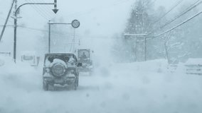 Snow covered vehicles driving cautiously during heavy snowfall through small town. Harsh winter conditions with huge piles of snow on roadsides and low visibility. Challenging car ride in wintertime. - Powered by Shutterstock - Get 15% off with code: PIKWIZARD15