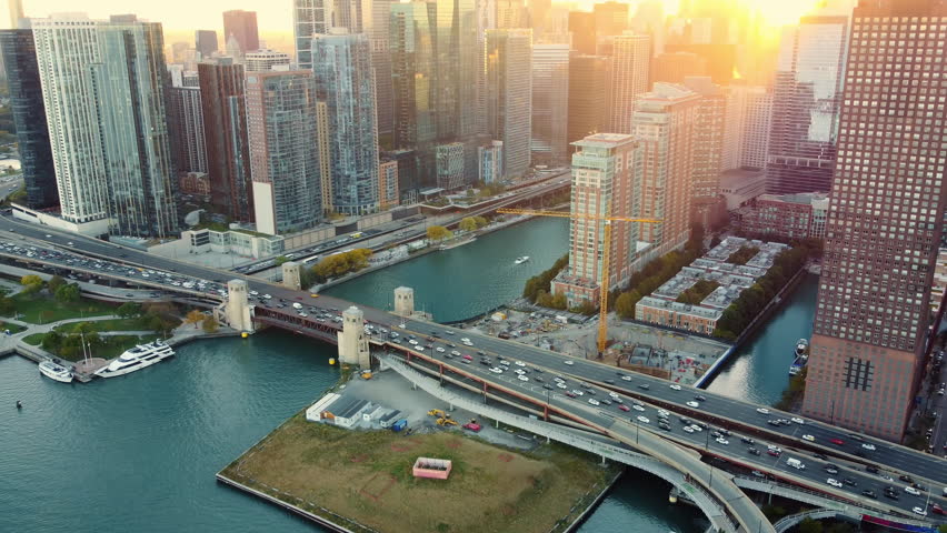 Chicago bridge and skyline at sunset with lens flare. Aerial view of Chicago's bridge and downtown buildings at sunset, with warm lens flare highlighting the urban architecture and river.