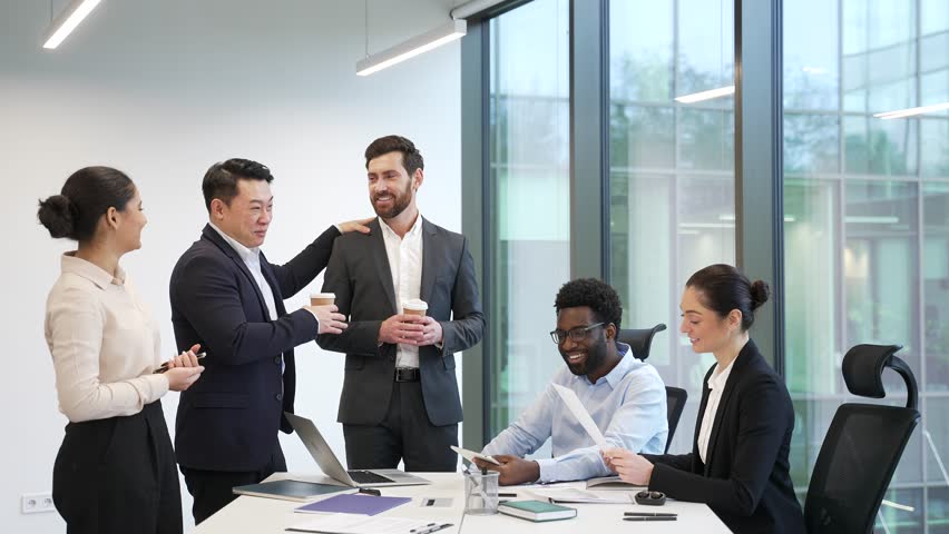 Colleagues communicate have a friendly chat during a coffee break. Group employees team business people coworkers having fun discussing project standing in office laugh indoor familiar cheerful joyful - Powered by Shutterstock - Get 15% off with code: PIKWIZARD15