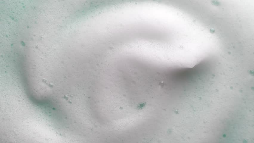 Foam texture swirl backdrop. Liquid soap bubbles background, Froth bubbles backdrop. Soap foam popping bubble rotating. Soap sud macro structure close-up. Clean, cleaning, washing, laundry. 