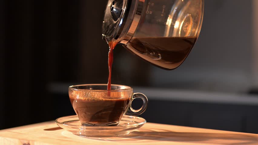 4K slow-motion of coffee being poured into a clear glass cup, highlighting the rich texture and aromatic warmth of the coffee.

