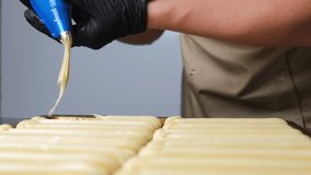 A pastry chef makes eclairs in a bakery. eclairs are baked in the oven. eclair production process. pastry bag with dough - Powered by Shutterstock - Get 15% off with code: PIKWIZARD15