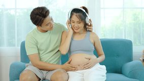 Beautiful pregnant wife with headphones enjoys listening to music for relaxation while husband take care of her. Mom and Dad feeling happy smiling peaceful while take care baby in the womb  - Powered by Shutterstock - Get 15% off with code: PIKWIZARD15