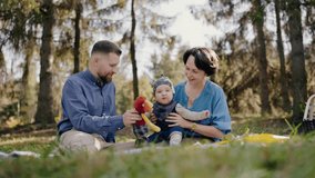 A young family with a baby spends quality time together, having a picnic in a sunlit forest park. Young Family Enjoying a Sunny Day at a Park Picnic - Powered by Shutterstock - Get 15% off with code: PIKWIZARD15