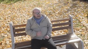 A senior man experiencing chest pain sits on a bench in a public park, visibly distressed. A passerby woman takes notice, showing concern for his well-being. - Powered by Shutterstock - Get 15% off with code: PIKWIZARD15