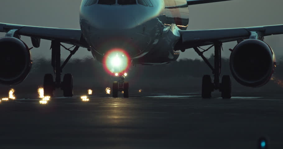 The wheels of a passenger plane travel along an illuminated runway. Flights on an airliner at night. High quality 4k footage