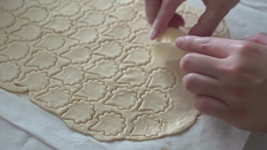 A cinematic and macro shot of biscuit making process - Hands stamping and cutting biscuit on raw dough.