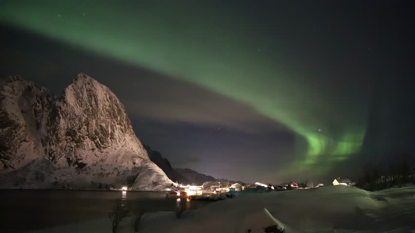 The aurora borealis dances across the night sky, painting it with vibrant waves of green, purple, and gold.