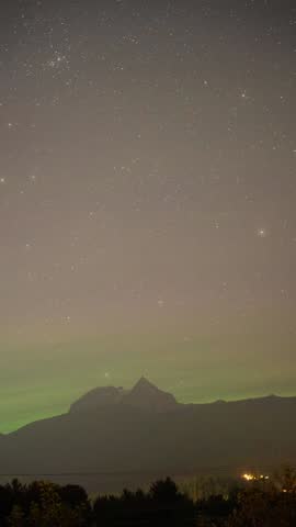 The aurora borealis dances across the night sky, painting it with vibrant waves of green, purple, and gold.