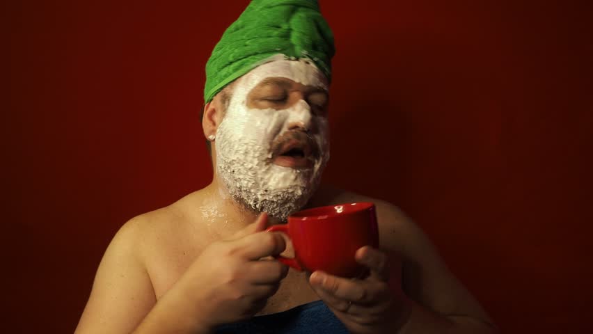 Funny fat man after shower in clay mask. Red background.