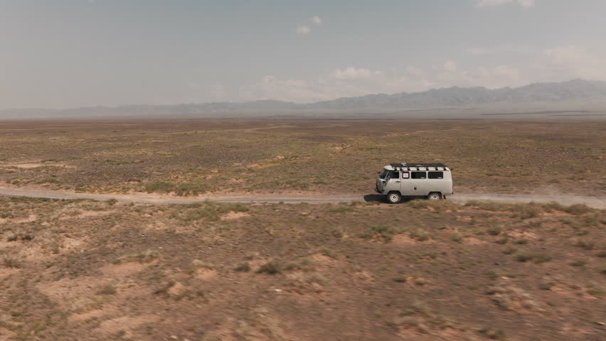 Aerial drone views of a UAZ van Cruising through the vast Gobi Desert of Mongolia at daylight in an extreme adventure