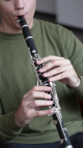 Clarinet player closeup top view. Clarinetist hands playing flute woodwind music instrument at home, selective focus. Musical instruments. Guy plays the oboe in education classroom. Hobby. 