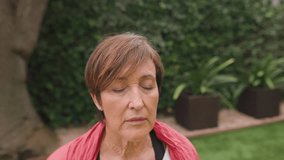 Elderly woman meditating with eyes closed in peaceful home garden setting. Senior couple practicing yoga together on yoga mats. Copy space. Close up, tracking shot, Horizontal, 4k video - Powered by Shutterstock - Get 15% off with code: PIKWIZARD15