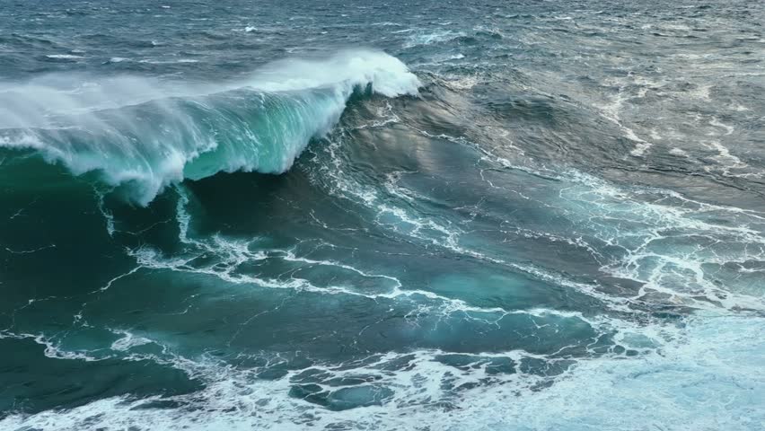 Powerful ocean waves crash against the shore. Aerial shot of gaint ocean waves. Slow motion