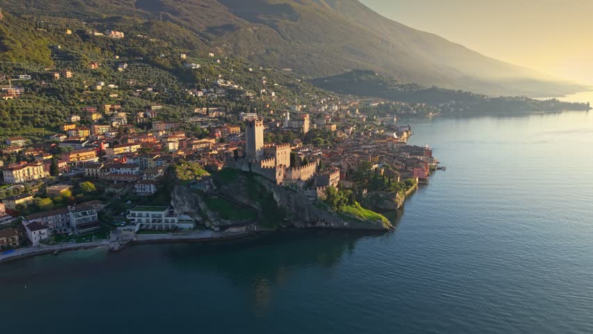 Stunning aerial shot of Malcesine along Lake Garda during sunset, Italy. Fly near Malcesine castle and village on the shores of Lake Garda