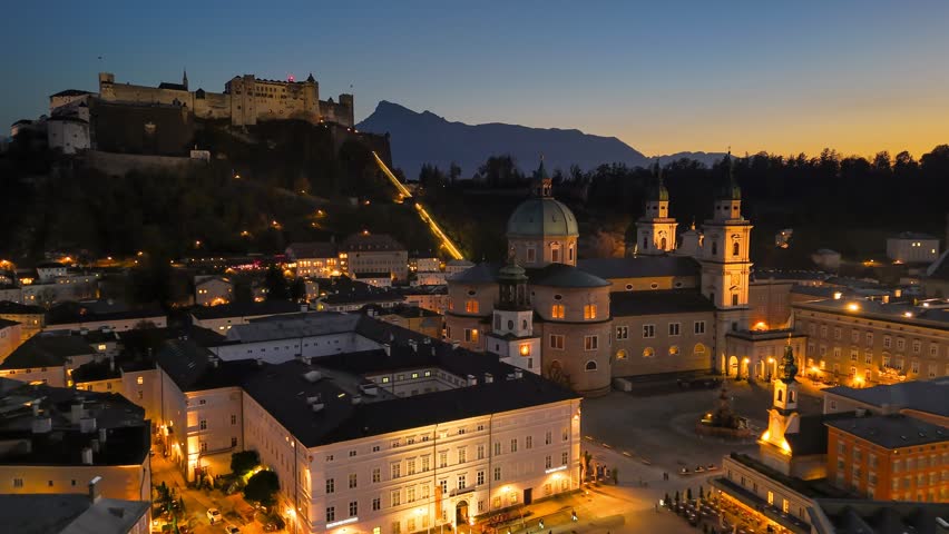 Sunset over Salzburg, Austria showcasing bustling city life and iconic fortress on the hill. Aerial HDR evening shot of Hohensalzburg fortress, city center and Salzburg Cathedral