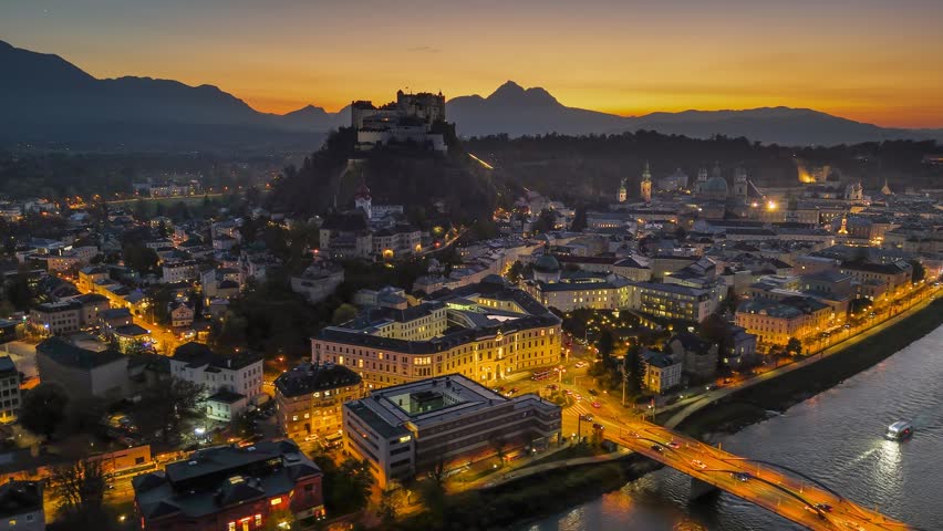 Beautiful sunset over Salzburg showcasing historic architecture and fortress. Fly over illuminated old town of Salzburg, Austria
