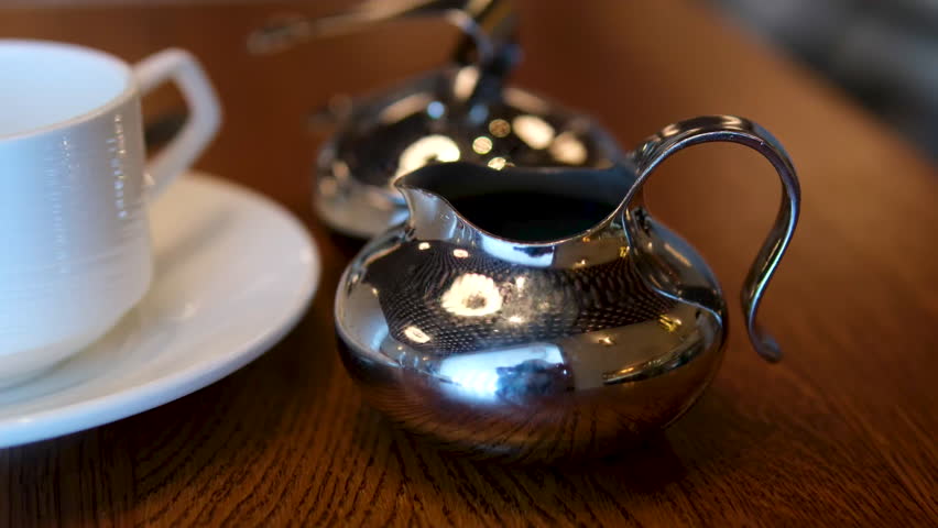 sugar bowl cup and milk jug Tea and Milk being Poured into the Ornate Tea Cup by a Setting of Tea and Biscuits and Sugar Bowl