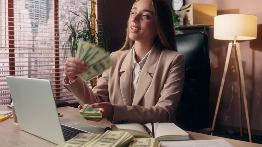 Rich successful satisfied Caucasian business woman female girl businesswoman office worker entrepreneur waving fan money throwing cash dollars winning jackpot salary profit finance promotion indoors