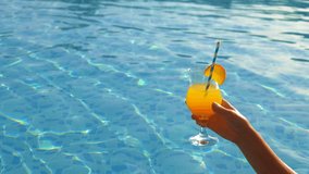 Glass with cocktail in hands near the pool. Elective focus. - Powered by Shutterstock - Get 15% off with code: PIKWIZARD15