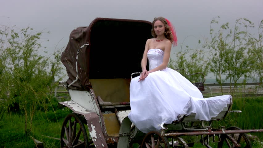 Slender young bride in a white wedding dress and a red ribbon in their hair