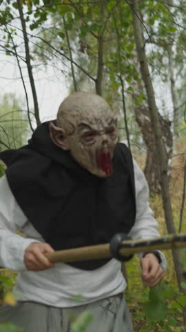Goblin with ax runs between trees and attacks girl with spear. Female warrior fights monster. Duel between young lady and evil creature horizon tilts