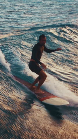 Man surfs the wave and does hand five trick by walking to the nose of the board. Aerial view of the male surfer riding the wave in the Maldives