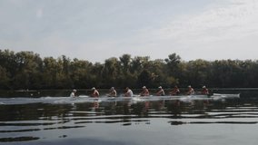 Rowing team training. Side view of 8 young caucasian male rowers, during a rowing practice, athlete sitting in a boat in the river Dnipro, rows through a calm water in autumn. 4k footage. City area in - Powered by Shutterstock - Get 15% off with code: PIKWIZARD15