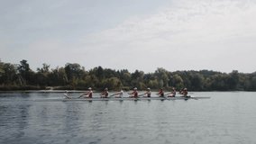 Rowing team training. Side view of 8 young caucasian male rowers, during a rowing practice, athlete sitting in a boat in the river Dnipro, rows through a calm water in autumn. 4k footage. City area in - Powered by Shutterstock - Get 15% off with code: PIKWIZARD15