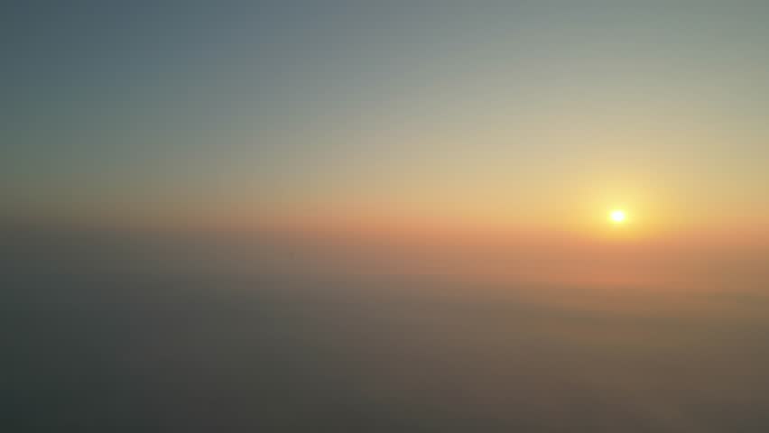 Sunrise breaking through morning fog over a vast landscape creating a tranquil, atmospheric scene