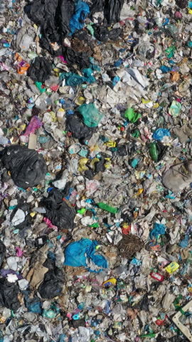 Aerial top view of open storage of solid household waste. Violation of the environment and land pollution with plastic bottles, bags and other hazardous waste. Vertical video
