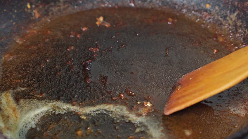 Cleaning burnt fat from surface of frying pan..