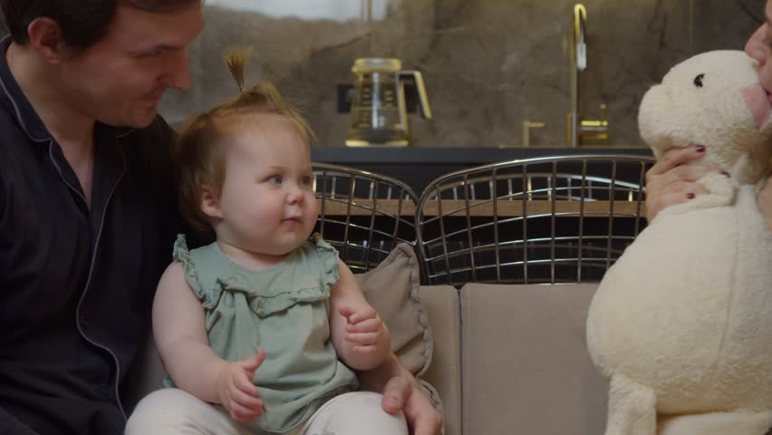 Little girl, about one year old, reaches for her favorite toy - a soft, plush rabbit. She hugs it close and smiles happily.