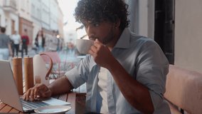 Serious man customer visitor client tourist traveler drink coffee urban cafe outdoors Indian Arabian guy booking hotel online order shopping male businessman student remote work using laptop in city - Powered by Shutterstock - Get 15% off with code: PIKWIZARD15
