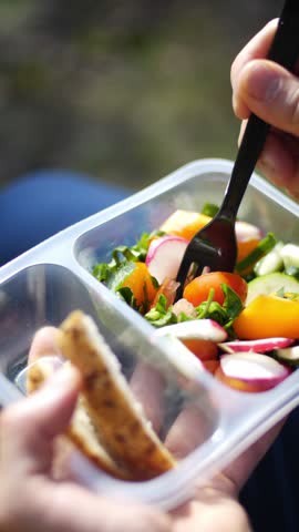 Food delivery, vegetable salad in a plastic disposable container vertical video. Food package, vegetable box, fresh healthy salad