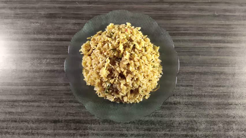 Adding cucumber slices to a plate of chicken fried rice