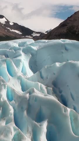 Amidst stunning landscape of Andes in Argentina, explore majestic glaciers of Patagonia. Shimmering blue ice formations contrast beautifully with rugged mountain backdrop, inviting adventure.