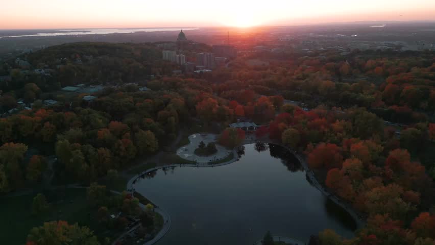 aerial shot over lac des castors in Montreal Mont Royal Park with Saint Joseph oratory in the background at sunset during fall season, Montreal CIty, Quebec province, Canada