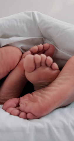 Love, cuddle and feet of couple in bedroom for relax, bonding and sleeping together. Marriage, care and relationship with closeup of people in bed at home in morning for resting, support and trust