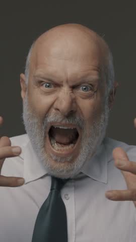 Angry aggressive corporate businessman shouting at camera, he is stressed and frustrated