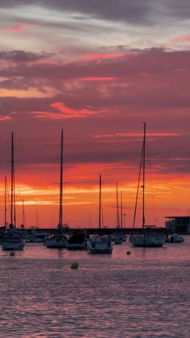A sunset over a body of water with several boats in the foreground in ibiza