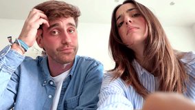 A young couple sits indoors on a comfortable sofa during their leisure time, appearing slightly frustrated and bored as they attempt to navigate an app and input a forgotten password - Powered by Shutterstock - Get 15% off with code: PIKWIZARD15