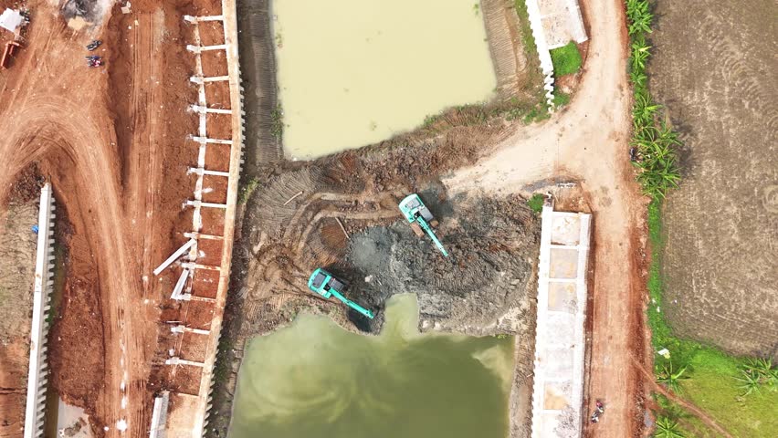 Aerial View From Top Of Two Escavators working inside Dam Contruction
