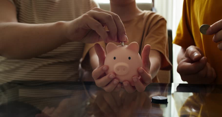 Family piggy bank for investment. Happy family throws coins into piggy bank. Financial business. Hands throw coins into piggy bank. Family business. People are counting coins. Girl with piggy bank