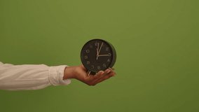A hand holds a clock against a green background, symbolizing time management and design - Powered by Shutterstock - Get 15% off with code: PIKWIZARD15